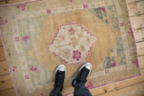Overhead view showing the scale of a distressed vintage Oushak rug with a magenta stepped medallion.