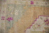 Close-up of the distressed, hand-knotted pile with pops of magenta and dusty teal on a gold field.