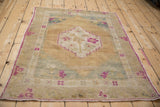 Angled view of a distressed Turkish Oushak rug highlighting its stepped medallion and fuchsia accents.