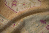 A detailed view of the vintage Oushak's time-softened texture in dusty gold, teal, and magenta.