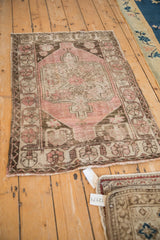 Distressed Oushak rug upper corner, with dusty blush pile and chocolate spandrel.