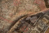 Distressed Oushak rug detail, folded, revealing dusty blush and antique ivory pile texture.