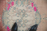 Distressed vintage Oushak runner showing worn pile, vibrant pink roses, and muted blue interlaced vines.