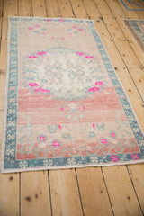 Distressed Oushak runner with heavy abrash, vibrant fuchsia florals, and faded blue border.
