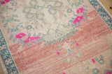 Distressed Oushak rug runner's abrash texture with pale rose, dusty blue, and vivid pink motifs.