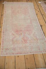 Angled view of the distressed Oushak runner's faded raspberry medallion and time-softened wear.