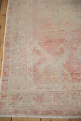 Close-up of a distressed Oushak rug's weave, showing the low pile in faded raspberry and silver.