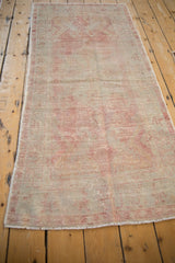 Full length angled view of a vintage Oushak runner with a soft raspberry and silver patina.