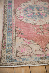Distressed Oushak rug border showing dusty denim blue, cochineal red, and beige tones.