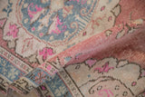 Distressed vintage Oushak rug's rolled edge, showing worn pile with denim blue and fuchsia patterns.