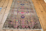 Lower corner of distressed Oushak rug, with magenta patterns and dark chocolate brown.