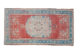 Distressed vintage Oushak rug, faded cherry red, ivory roundel medallion, turquoise border.