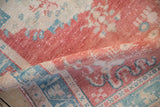 Aged pile texture of distressed vintage Oushak rug in faded cherry red and dusty turquoise.