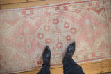 Distressed texture and faded dusty rose floral motifs on a vintage Oushak rug runner.