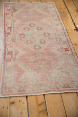 Vintage distressed Oushak runner, its faded dusty rose and beige pile.