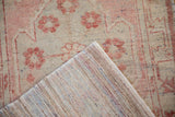 Distressed Oushak rug runner: faded dusty rose florals and colorful rag rug wefting.
