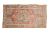 Vintage distressed Oushak rug with a faded red medallion, dusty turquoise accents, and an ivory field.