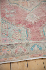 The boteh main border of a distressed Oushak rug featuring a low pile and faded turquoise motifs.
