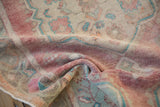 Evenly worn, low pile texture of a distressed Oushak rug in faded red and turquoise.