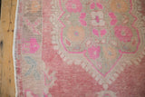 Distressed Oushak rug's vibrant fuchsia and raspberry geometric arabesque border with selvage.
