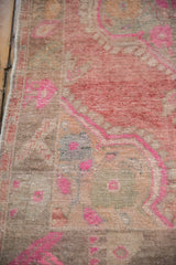 Distressed vintage Oushak pile with geometric arabesques in raspberry and fuchsia tones.