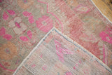 Distressed Oushak rug corner: fuchsia and beige pile, hand-knotted foundation, and even wear.