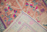 Distressed rose gold pile of vintage Oushak rug with faint foundation visible, folded to show colorful back weave.