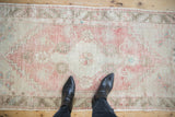 A personal view of a distressed Oushak rug, showing its soft texture and faded dusty rose medallion.