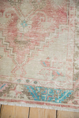 Detail of the distressed, low-pile texture and turquoise floral border on a vintage Oushak rug.