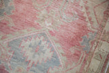 Distressed vintage Oushak rug's low pile, revealing blush, beige, and slate blue patterns.