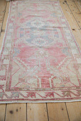 Textured detail of the distressed Oushak runner showing pale red and blue motifs, with even wear.