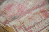 Distressed hand-knotted texture of a folded Oushak rug in soft blush, beige, and blue.