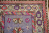 Distressed Oushak rug corner, soft lavender field, pink floral motifs, textured pile, geometric borders.