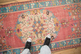 Distressed vintage Oushak runner showcasing central medallion, germinating plants, and floral motifs in raspberry and turquoise.