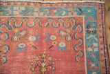Distressed Oushak rug corner, even wear revealing turquoise border and raspberry red motifs.