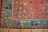Distressed Oushak rug corner showing textured raspberry, turquoise, ivory traditional floral motifs.