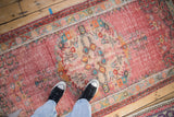 Distressed Oushak rug pile showcasing worn raspberry red, turquoise, and saffron floral patterns.
