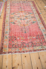 Distressed Oushak runner texture in faded raspberry red with visible floral motifs.