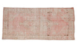 Vintage distressed Oushak runner in pale pink and ivory with a faded diamond center medallion.