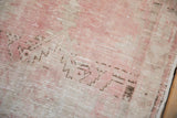 Worn texture of a distressed Oushak rug showing knot heads in pink and silver tones.