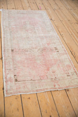 A vintage distressed Oushak runner in pale pink and ivory viewed from an angle.