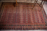 Worn cranberry and blue tribal pattern of an antique Persian Malayer rug.