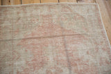 Visible wear and soft tones on the distressed vintage Oushak rug surface, showing wefting striations.