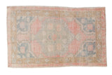 Vintage distressed Oushak rug with a scalloped medallion in pale pink, jade green, and dusty blue.