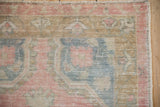 Close-up on the corner of a distressed Oushak rug showing even wear across the pale pink and blue pile.