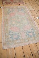 Angled view of a vintage Oushak rug, showcasing its time-softened texture and faded pastel floral design.