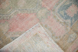 Hand-knotted foundation and distressed, low-pile texture of a vintage Oushak rug corner.