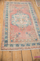 Intact side selvage and worn dusty turquoise border on a vintage distressed Oushak rug.