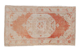 Vintage distressed Oushak rug with a concentric rust medallion and floral motifs on an ivory field.