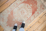 A distressed vintage Oushak rug in rust and ivory shown from an overhead perspective to illustrate scale.